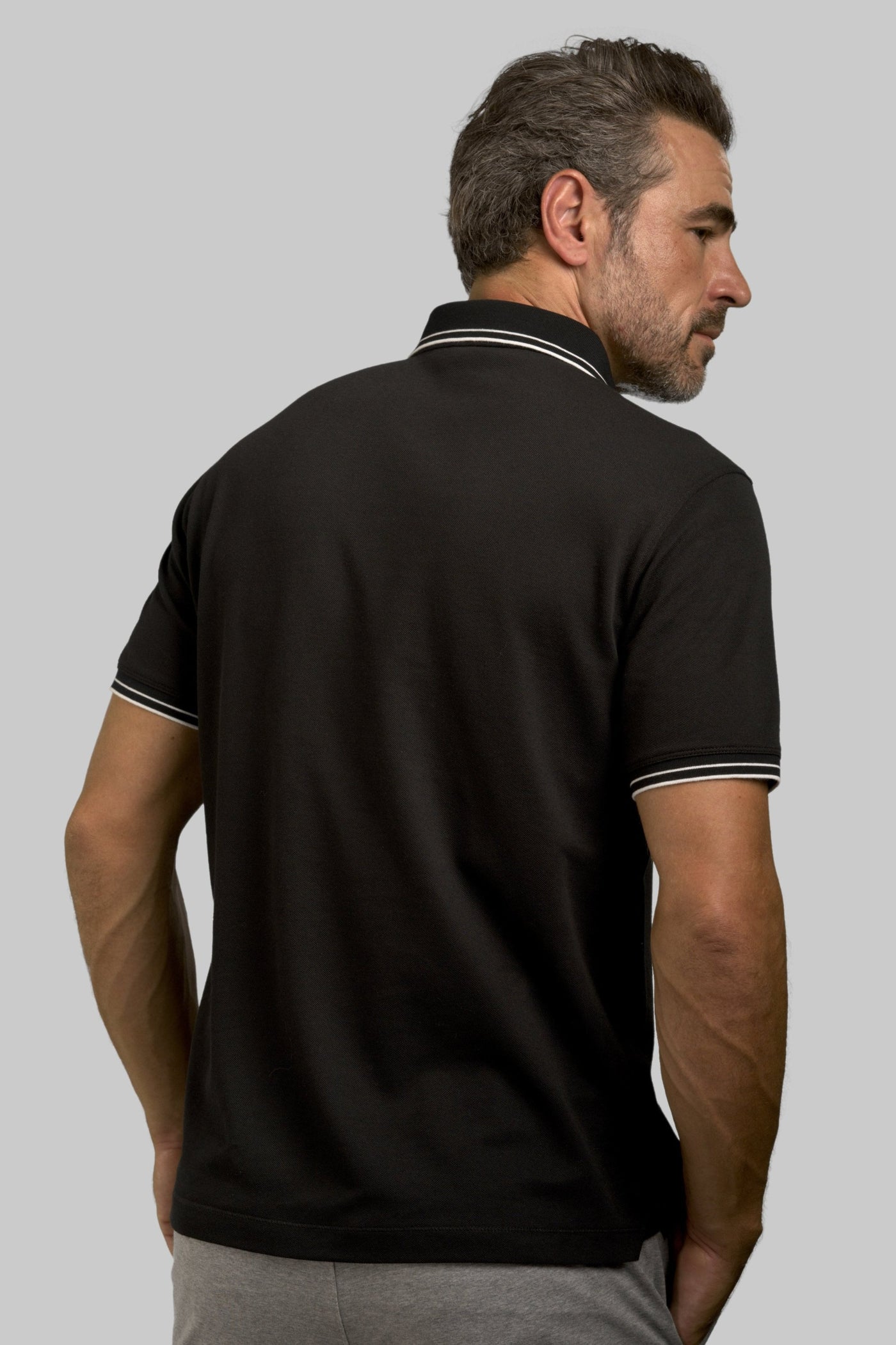 Buki's "happy" polo shirt features a "happy" flower motif on the chest. In Black.